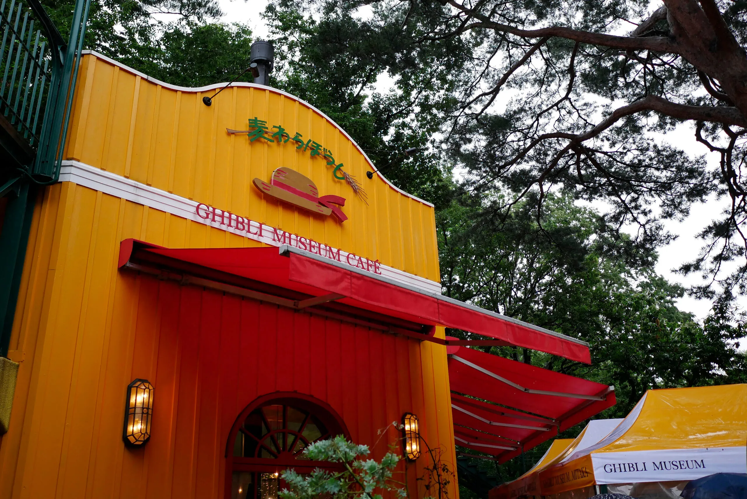 Bright yellow Ghibli Museum Café exterior with red awnings in Tokyo.