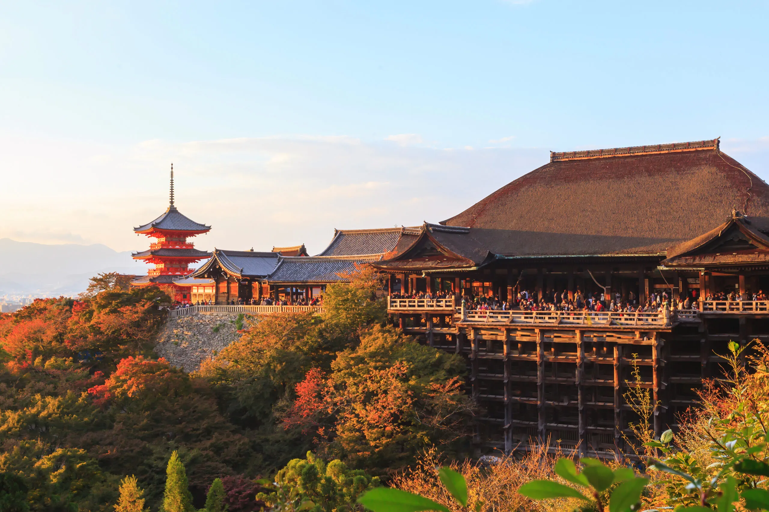 Kiyomizu-dera’s wooden stage amid autumn foliage at sunset.