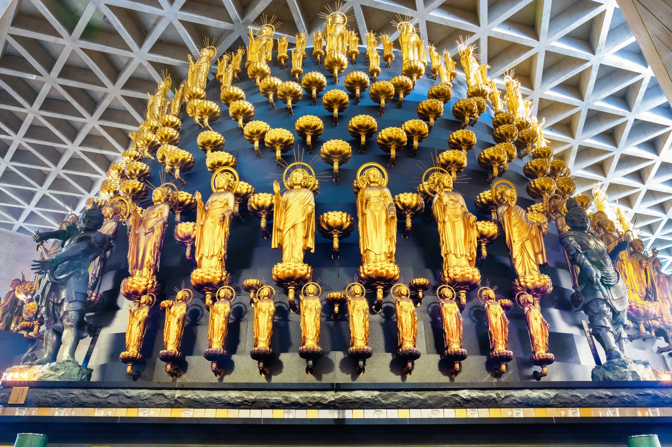 A unique altar featuring golden statues of Kannon (Buddhist deities of mercy) intricately arranged in a modern design at Isshin-ji Temple in Osaka, Japan