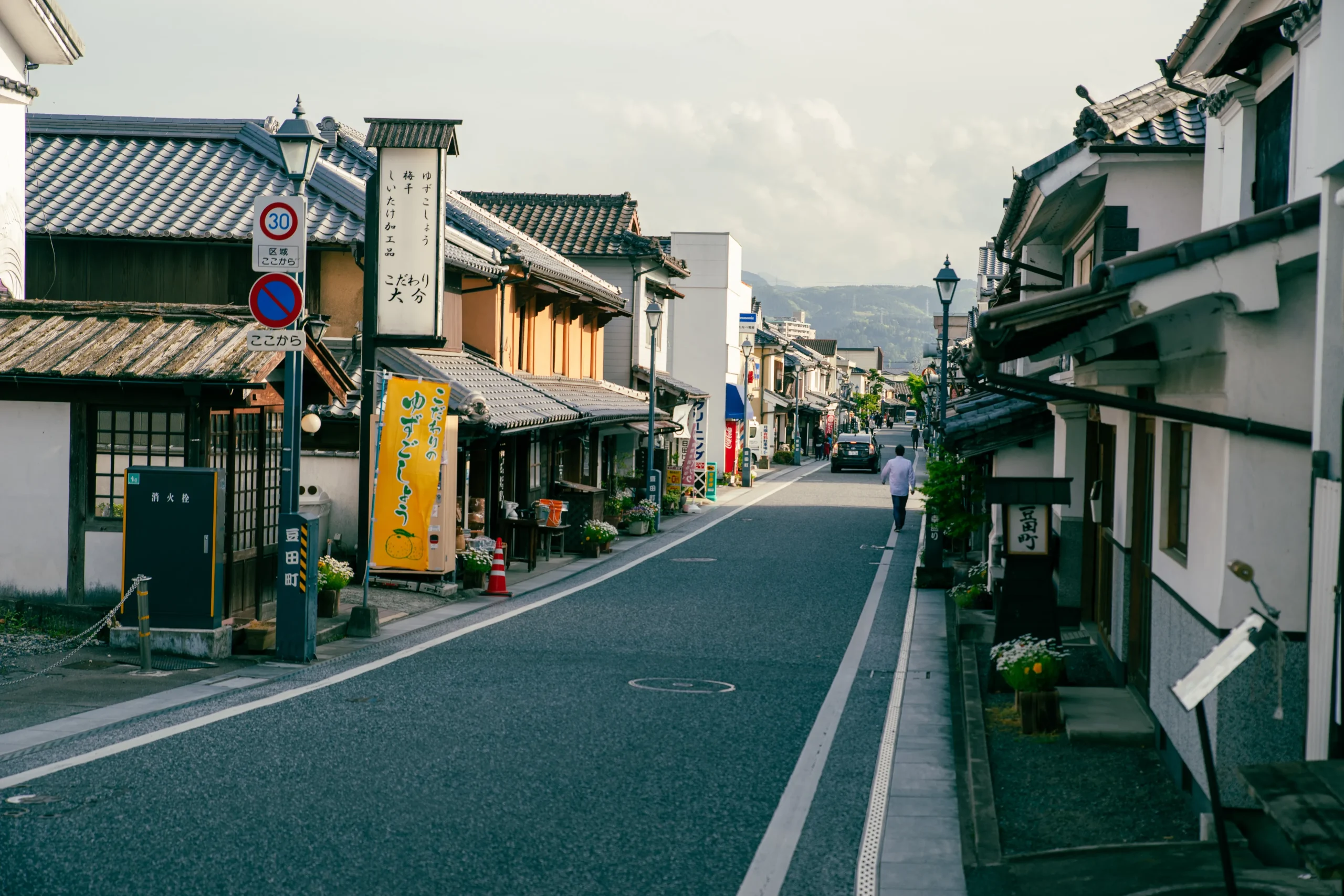 A historic wooden building representing traditional Japanese hot spring culture, with a charming exterior and tourists enjoying photography outside