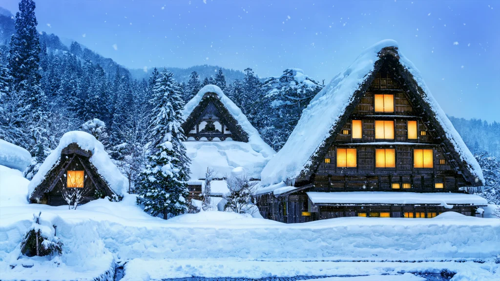 Traditional thatched-roof houses in Shirakawa-go, covered in thick snow with warm glowing lights during winter.