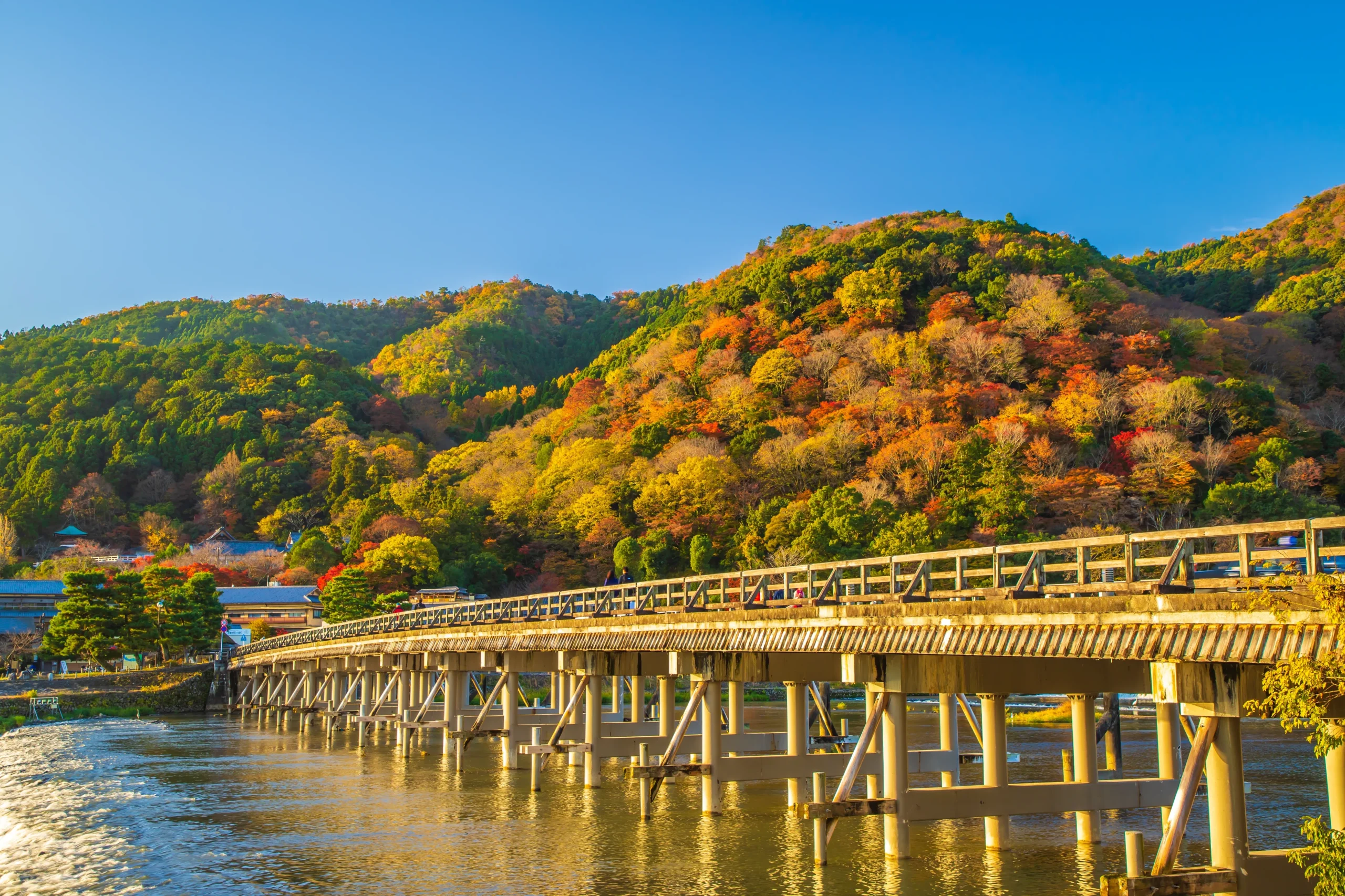 Togetsukyo Bridge spanning the Katsura River in Kyotoâ€™s Arashiyama district, framed by mountains blanketed in vibrant autumn colors