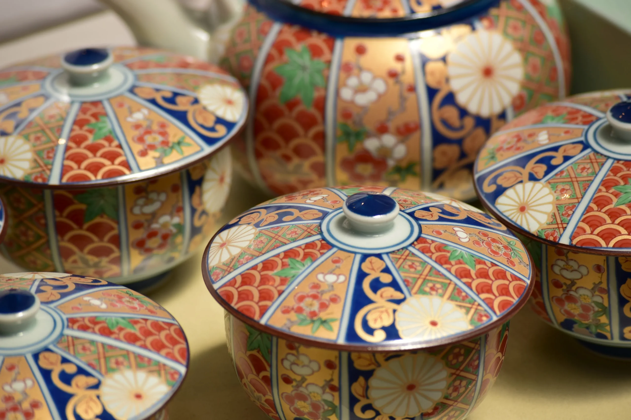 A close-up view of a beautifully designed Imari ware tea set with vibrant patterns in red, blue, and gold, showcasing intricate traditional Japanese artistry.