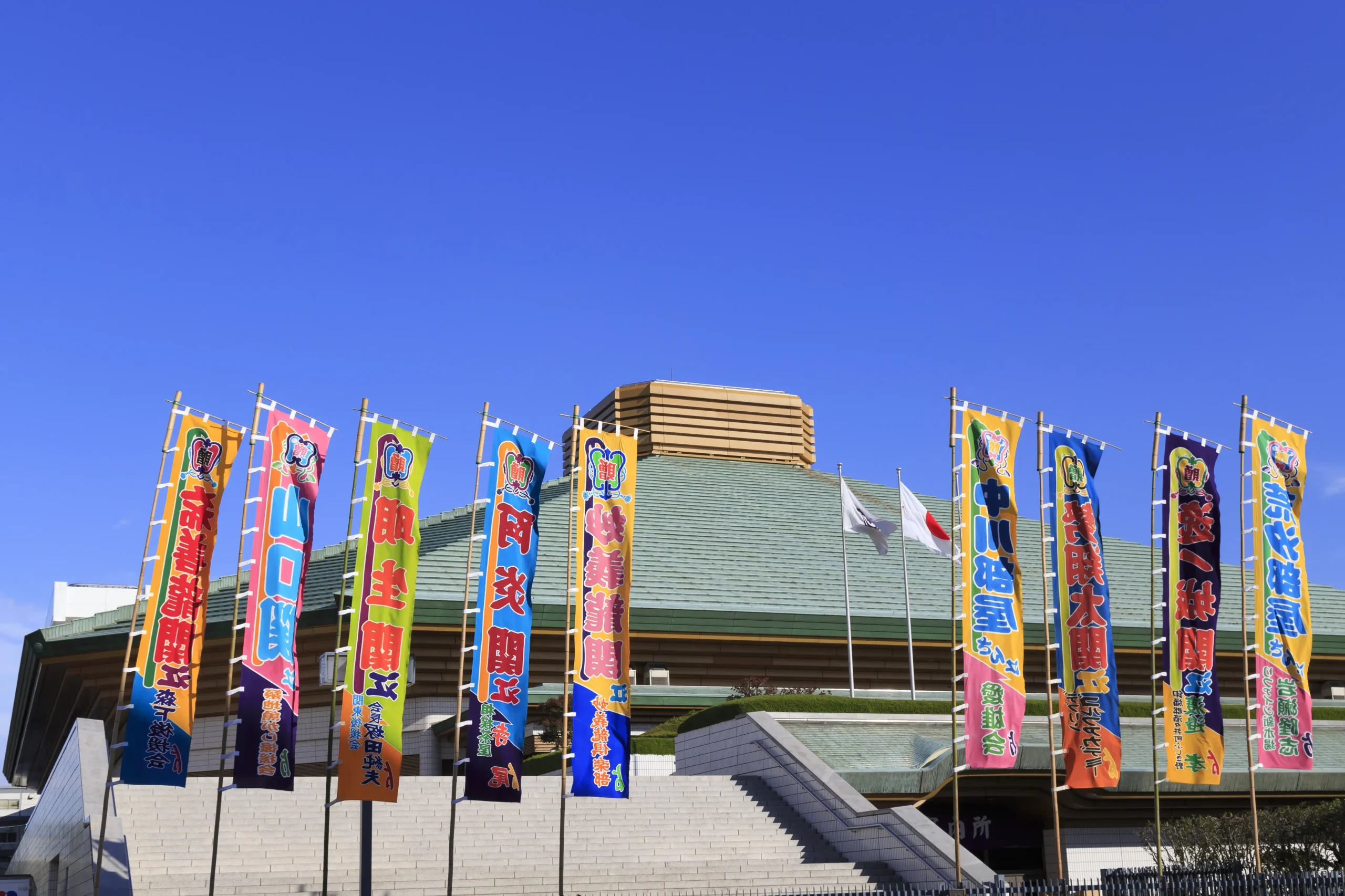 Ryōgoku Kokugikan sumo arena in Tokyo with colorful flags and clear blue sky