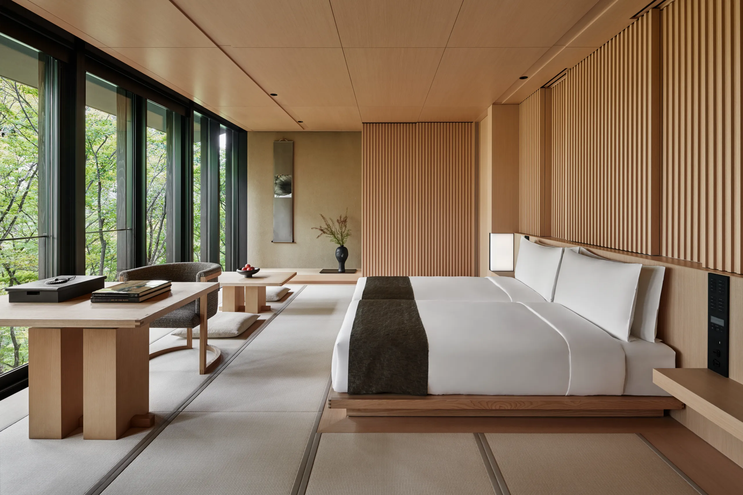 Minimalist luxury suite at Aman Kyoto with tatami flooring and forest view through wide windows.