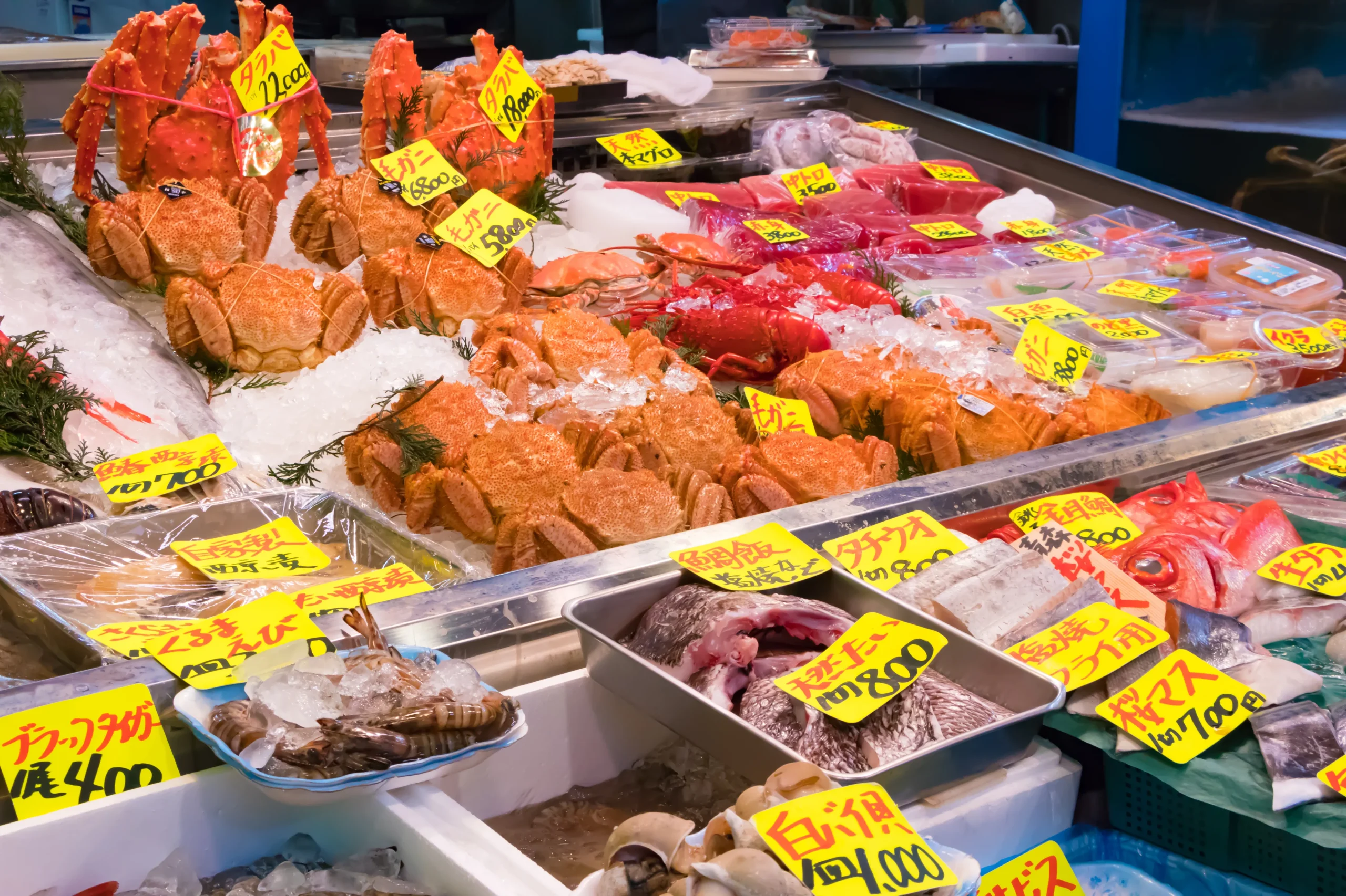 A vibrant seafood stall at Tokyo’s Tsukiji Market, displaying fresh crabs, fish, and shellfish with handwritten price tags.