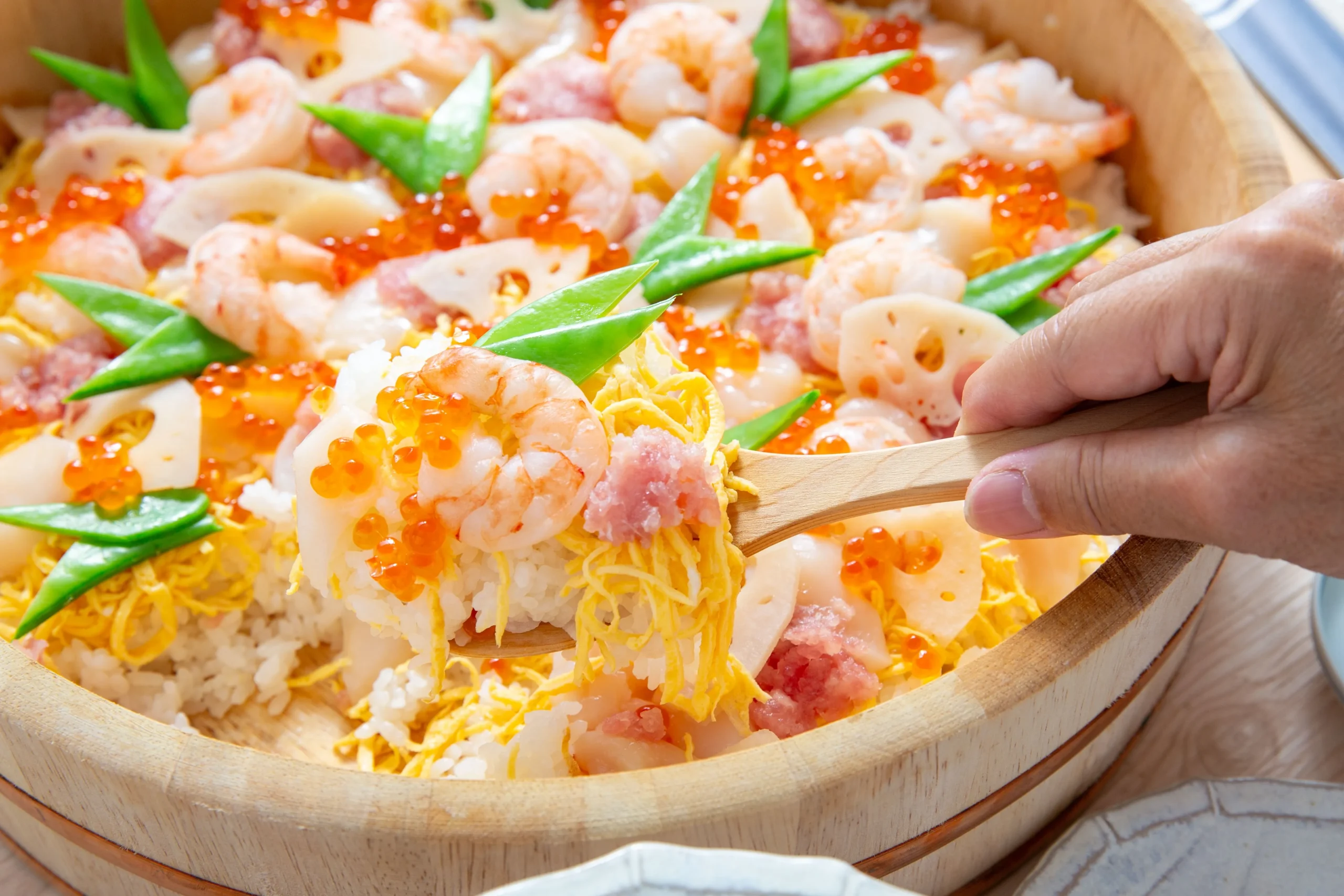 Colorful chirashi sushi with shrimp, roe, and vegetables in a wooden bowl