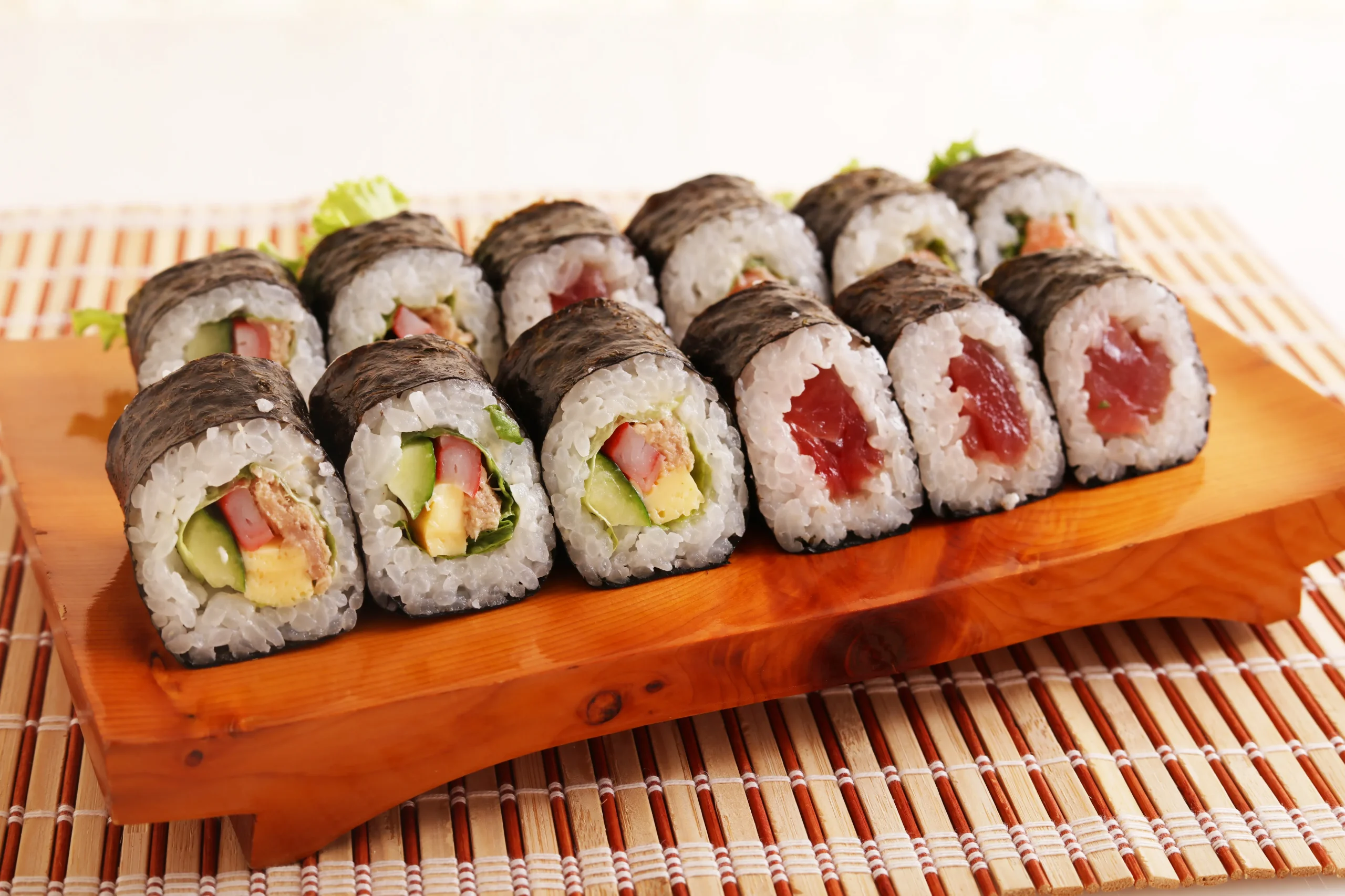 Assorted maki sushi rolls with vegetables and tuna on a wooden tray