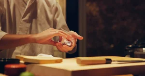 Sushi chef carefully preparing nigiri by hand at a Japanese restaurant