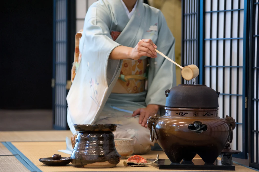 Japanese tea ceremony with woman in kimono preparing matcha using traditional tool