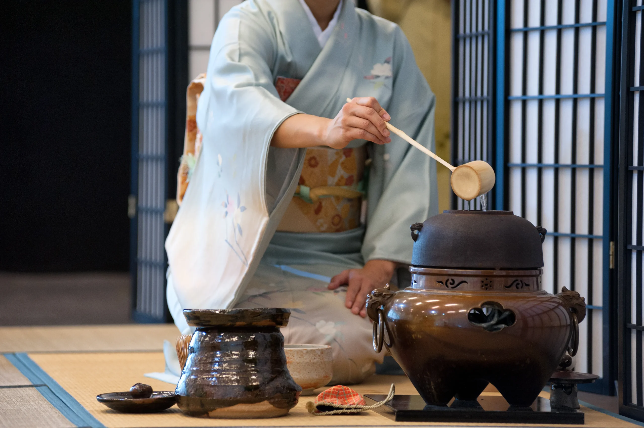 Japanese tea ceremony with woman in kimono preparing matcha using traditional tool