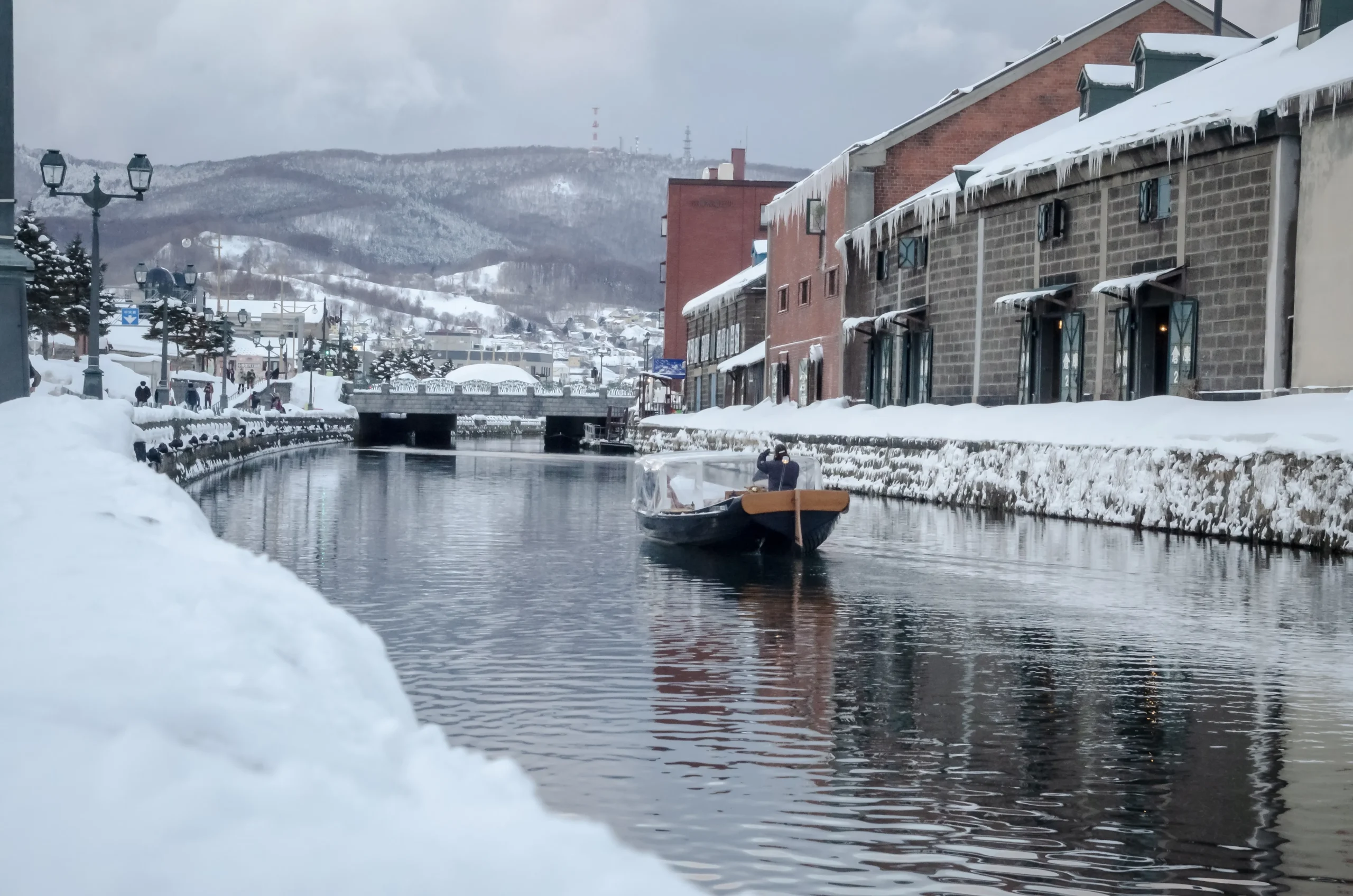 Snowy Otaru Canal with brick warehouses and winter boat ride, Hokkaido, Japan