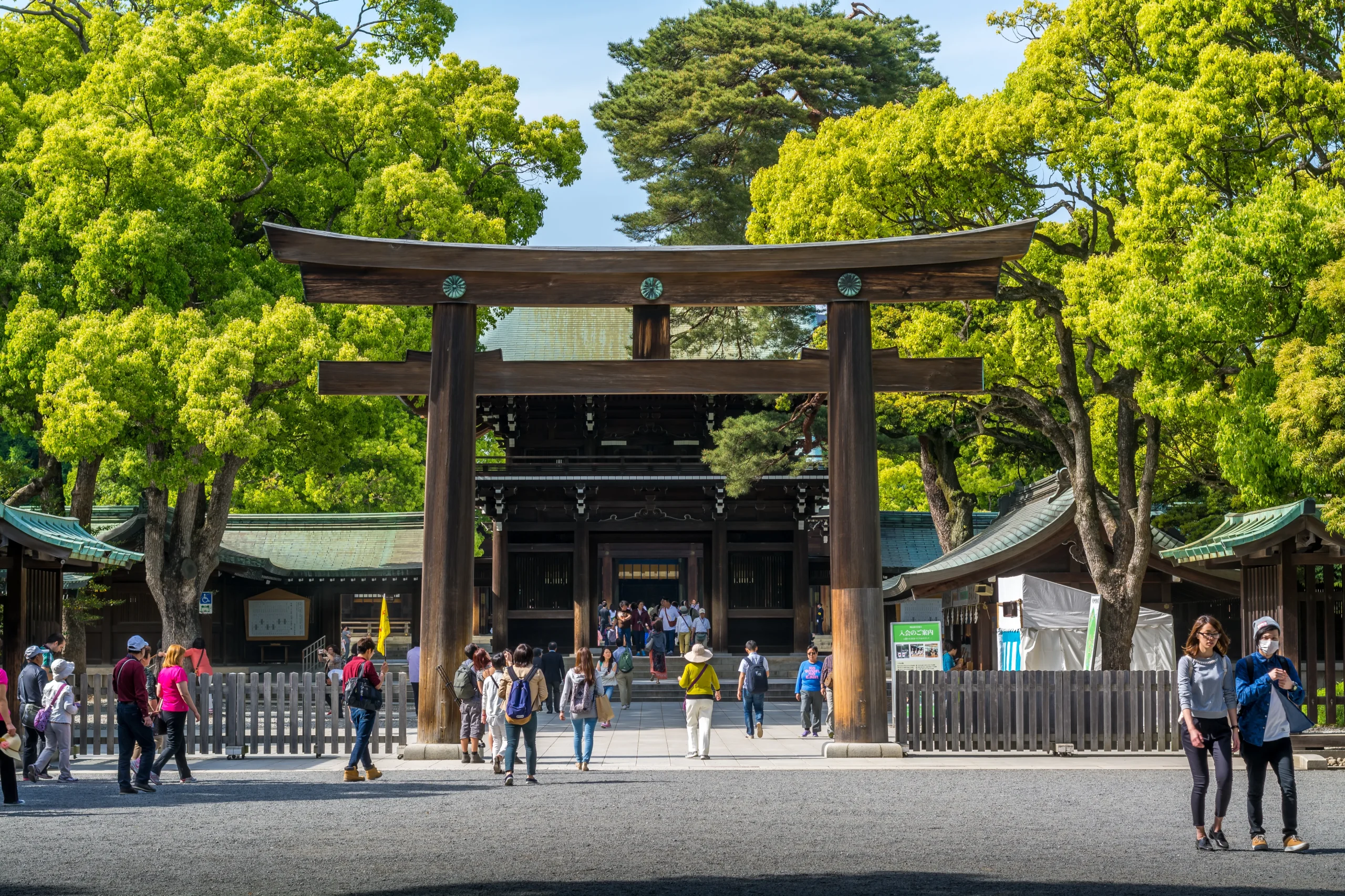Large wooden torii gate and visitors at Meiji Shrine in Tokyo