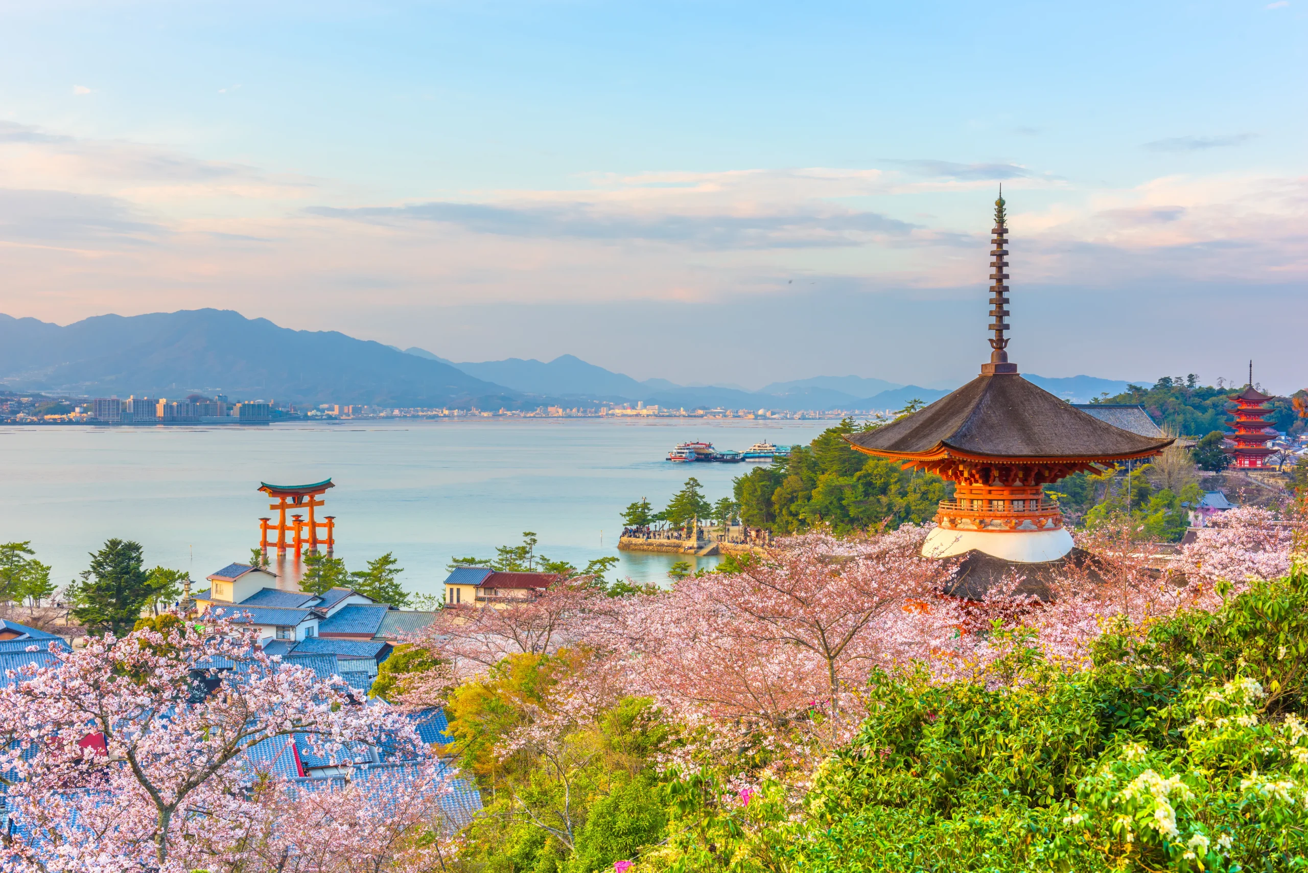 Pagoda and torii gate on Miyajima Island surrounded by cherry blossoms and sea views