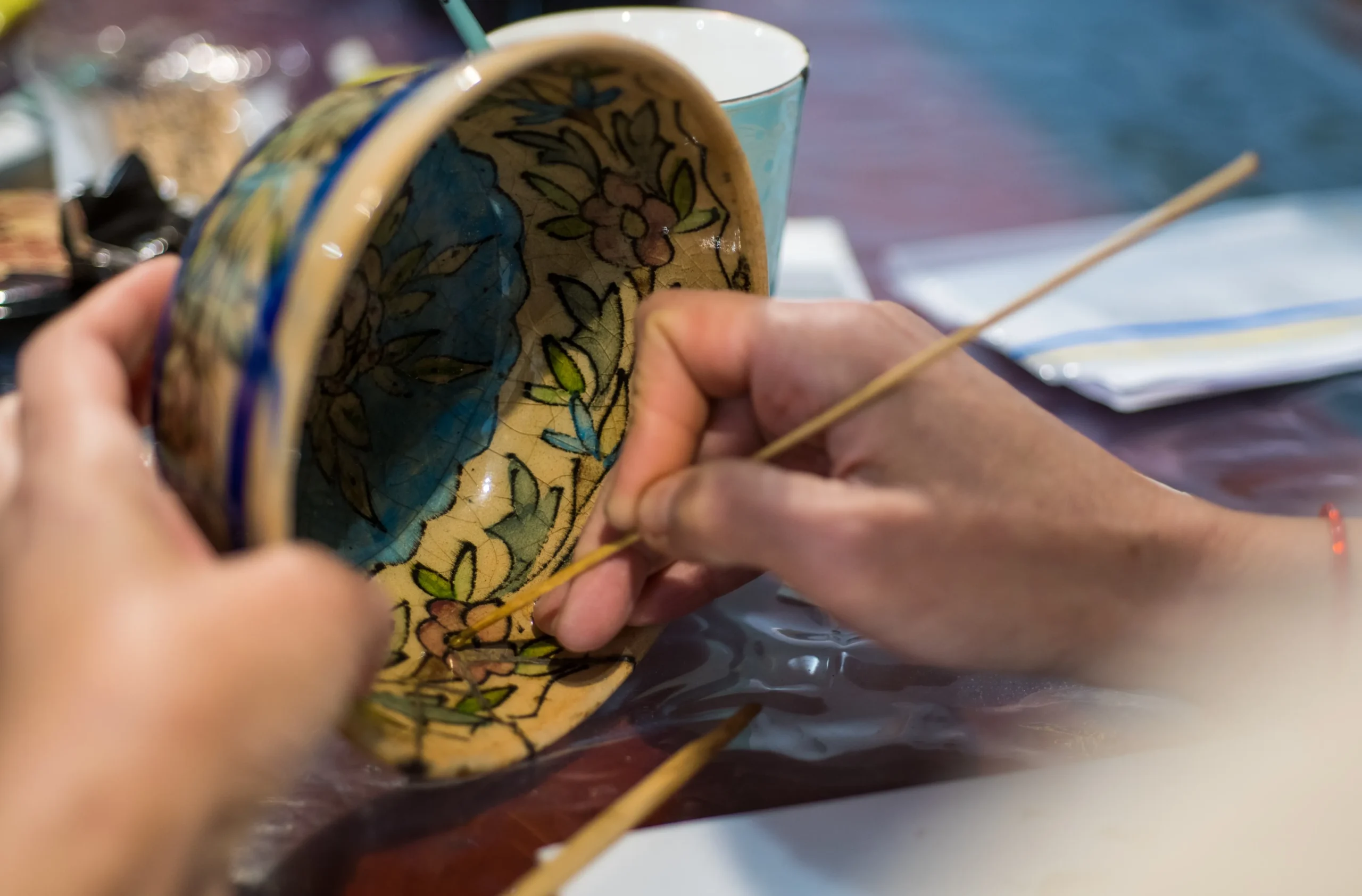 Hands repairing a pottery bowl using kintsugi lacquer technique in a Japanese workshop
