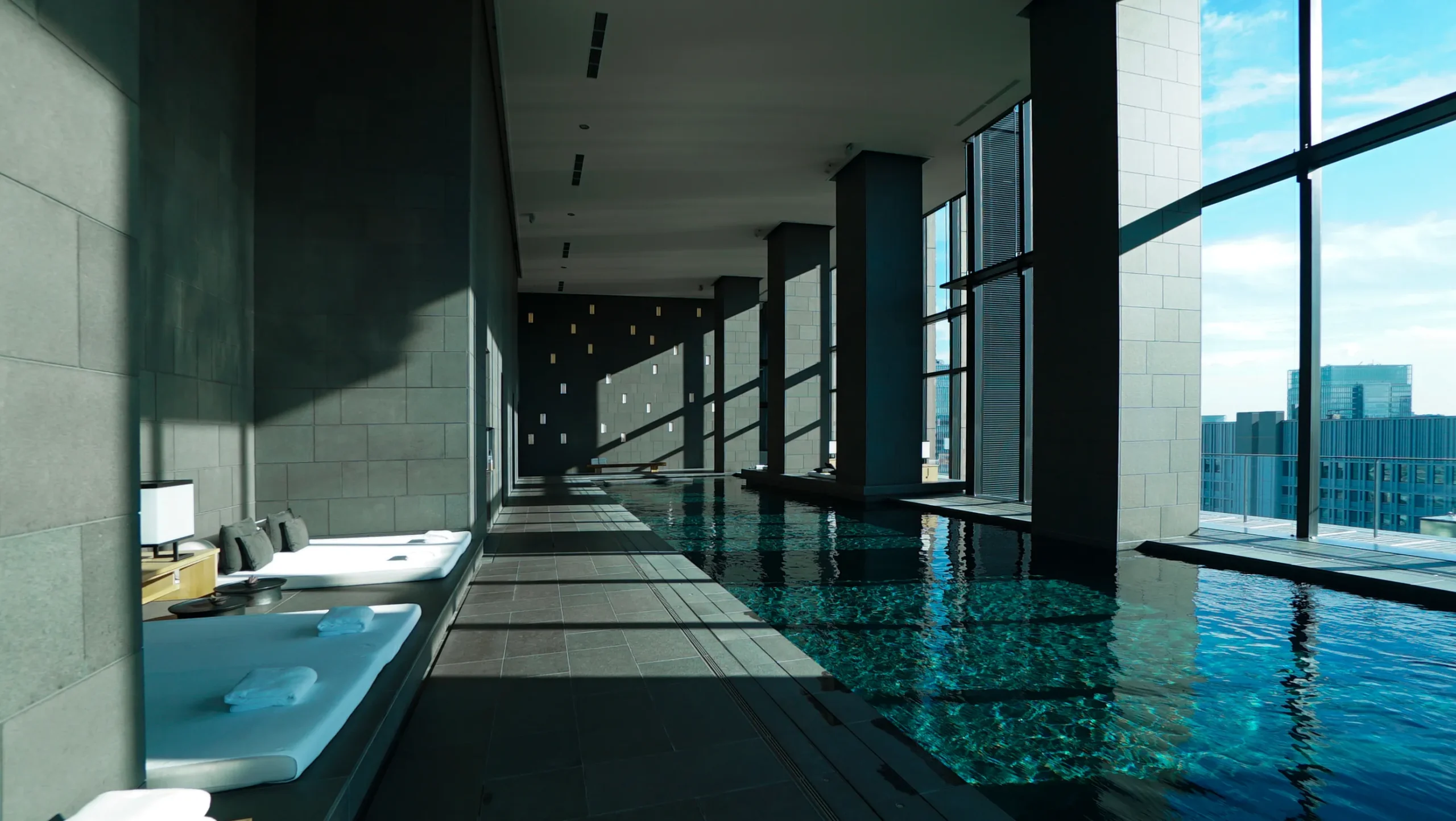 Luxury indoor swimming pool at Aman Tokyo hotel with floor-to-ceiling city views.