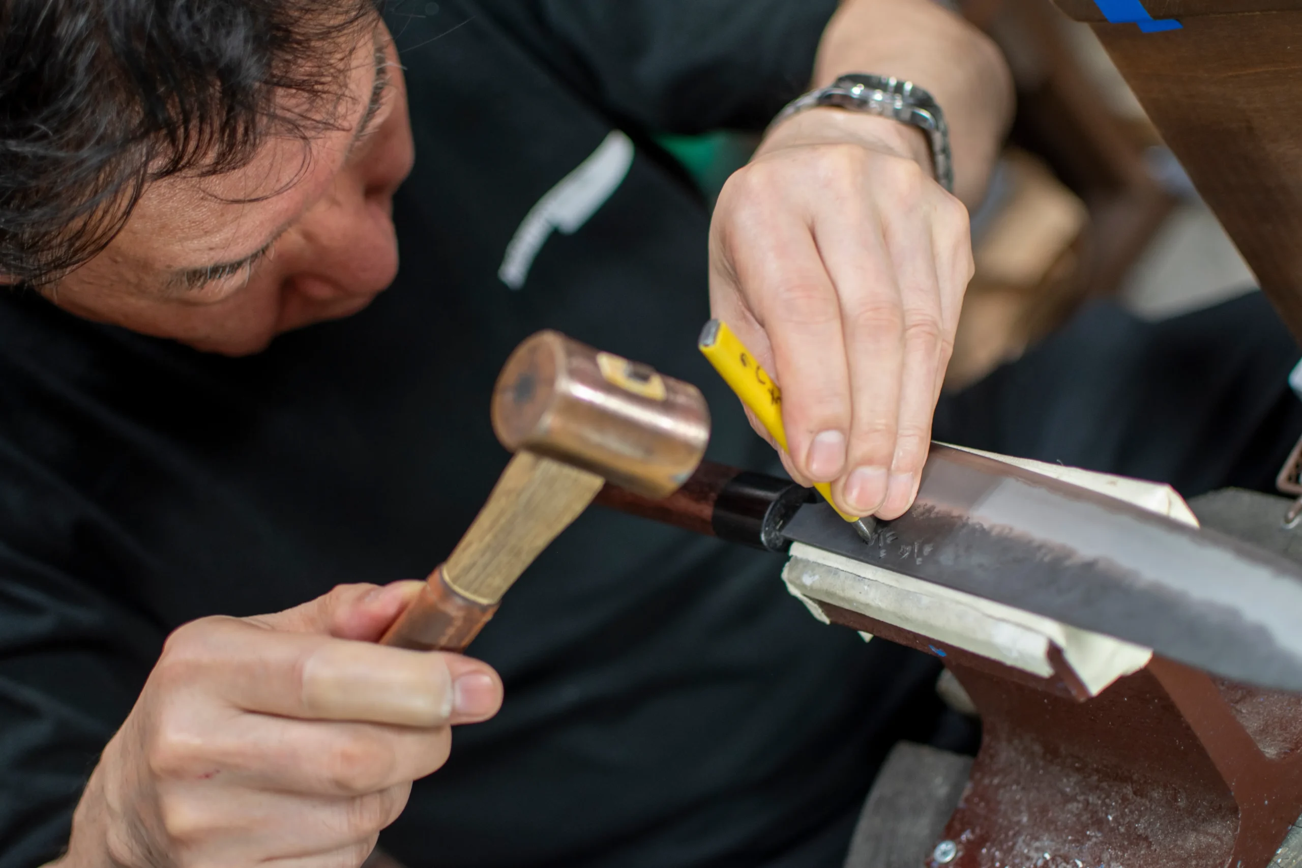 Craftsman engraving a name on a Japanese kitchen knife at a knife shop.
