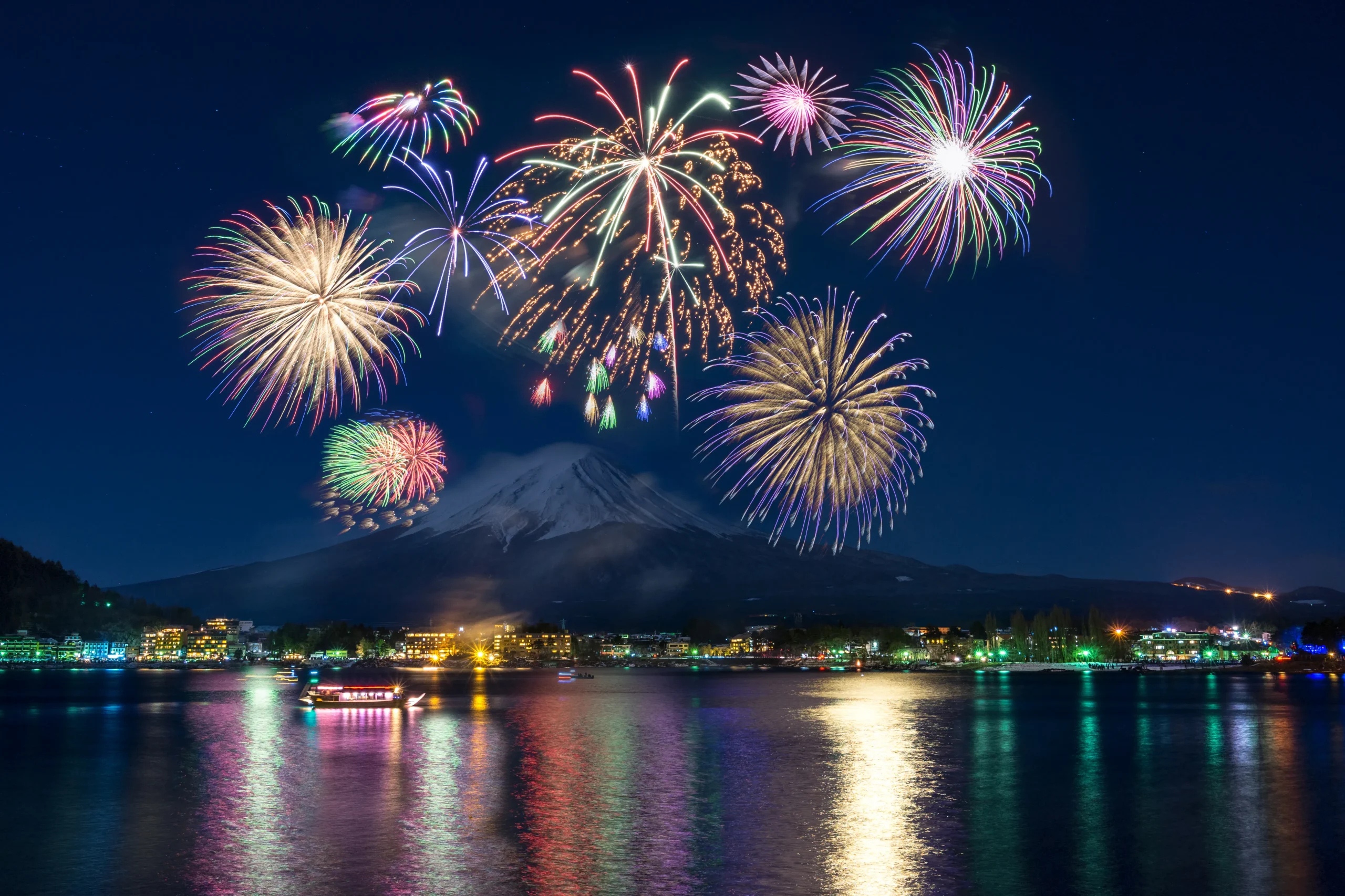 Vibrant winter fireworks display over Lake Kawaguchiko with Mount Fuji at night.