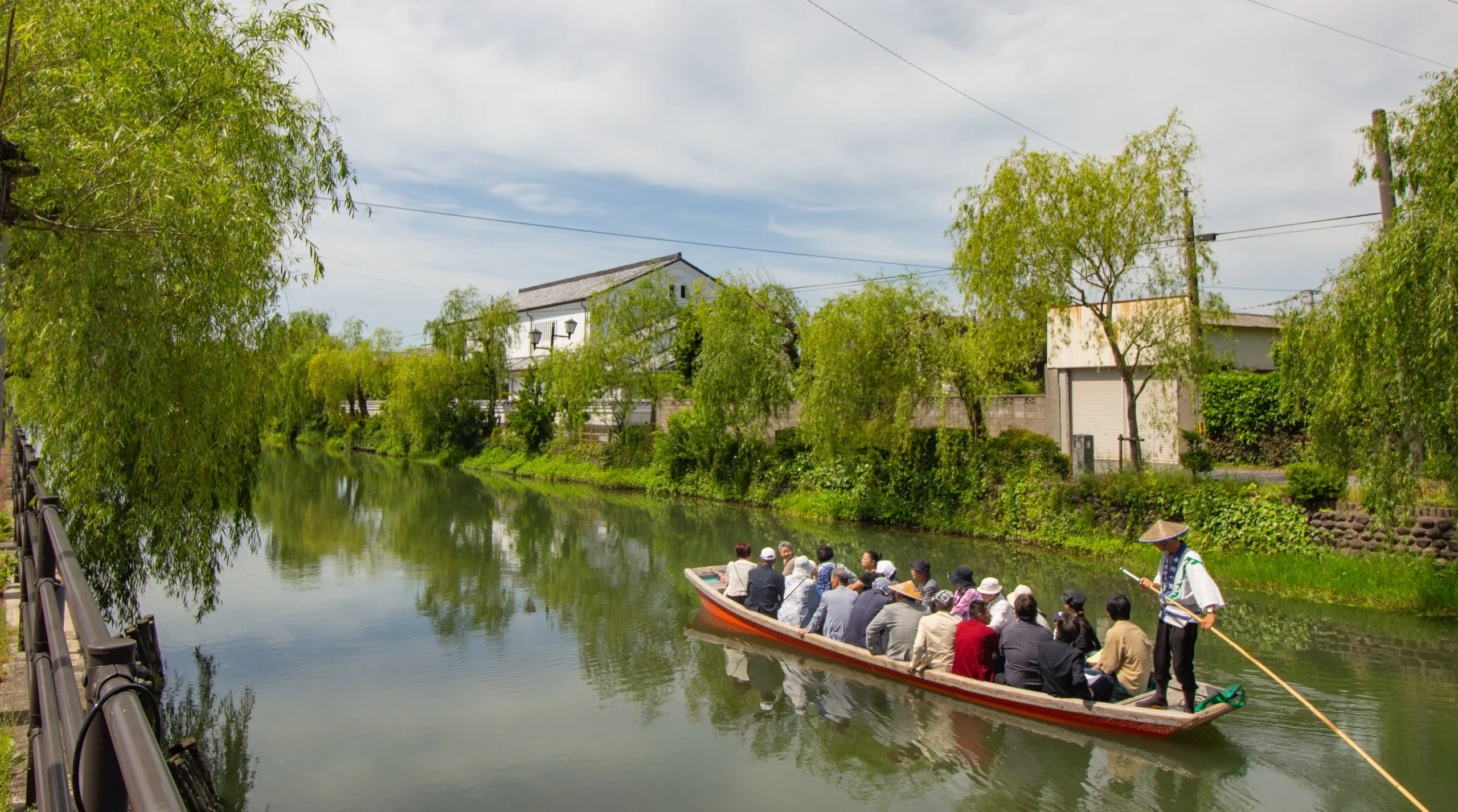 Traditional Yanagawa river cruise boat with passengers and a boatman in Fukuoka.