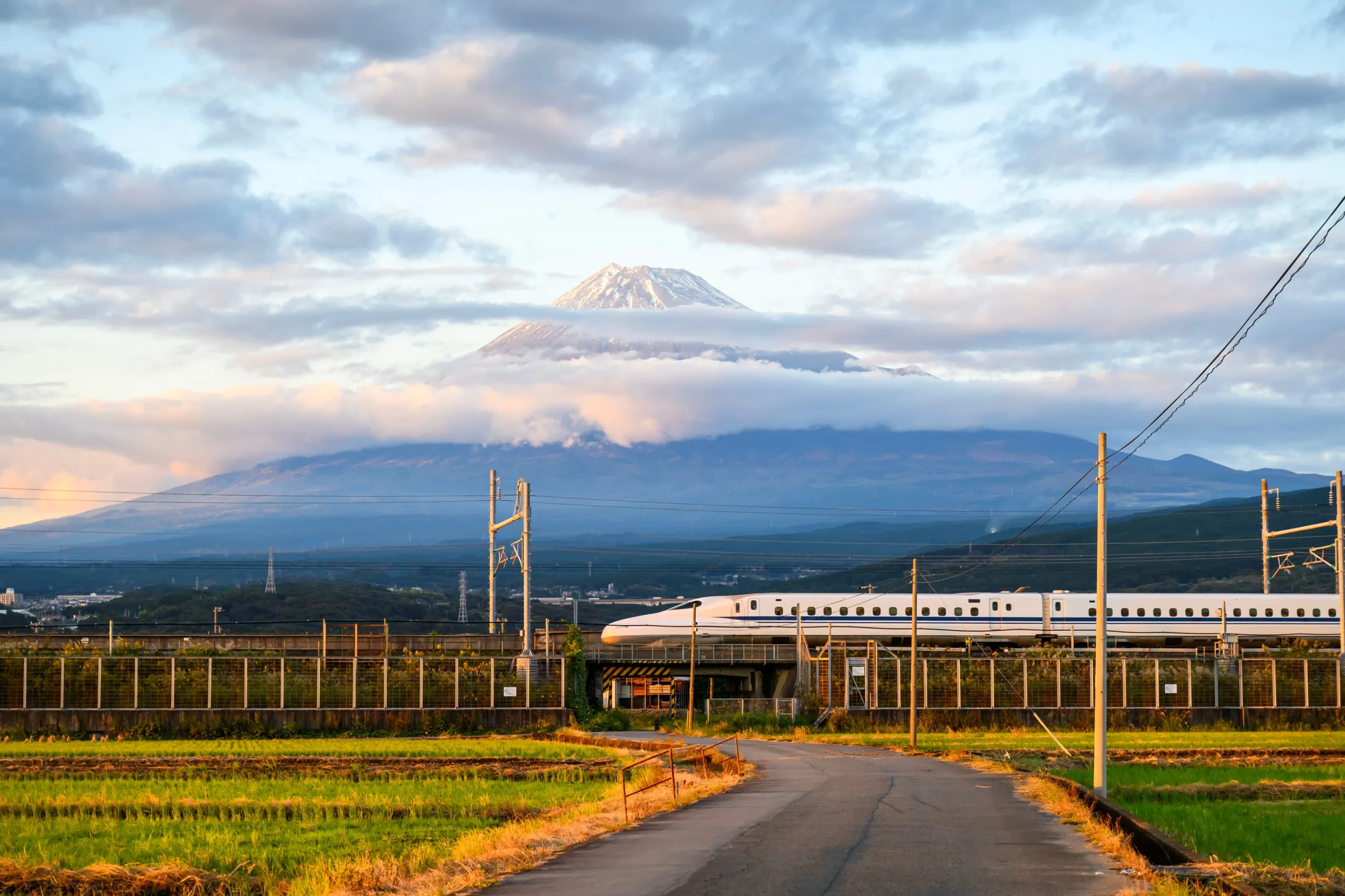 Shinkansen bullet train passing Mount Fuji with countryside view in Japan