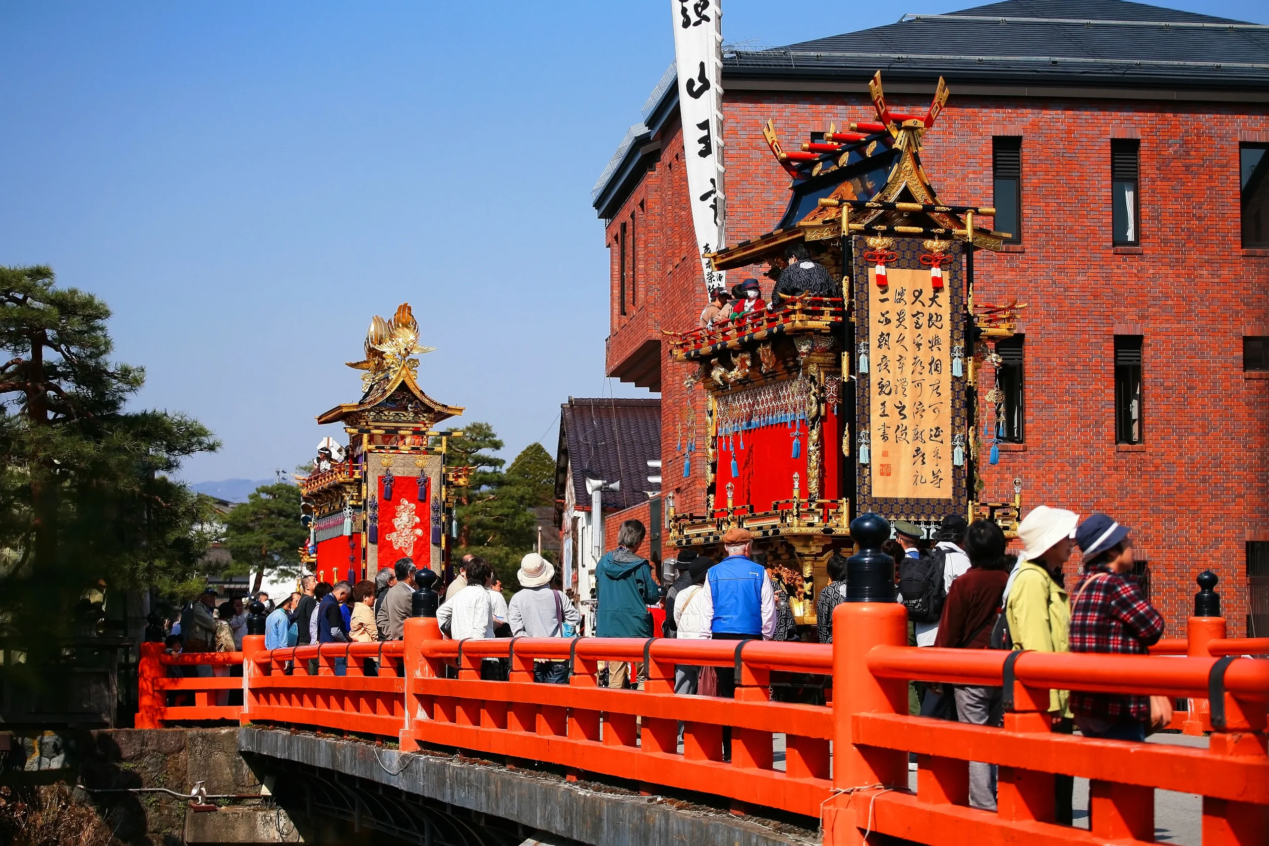 Takayama Autumn Festival with decorated floats crossing bridge and spectators