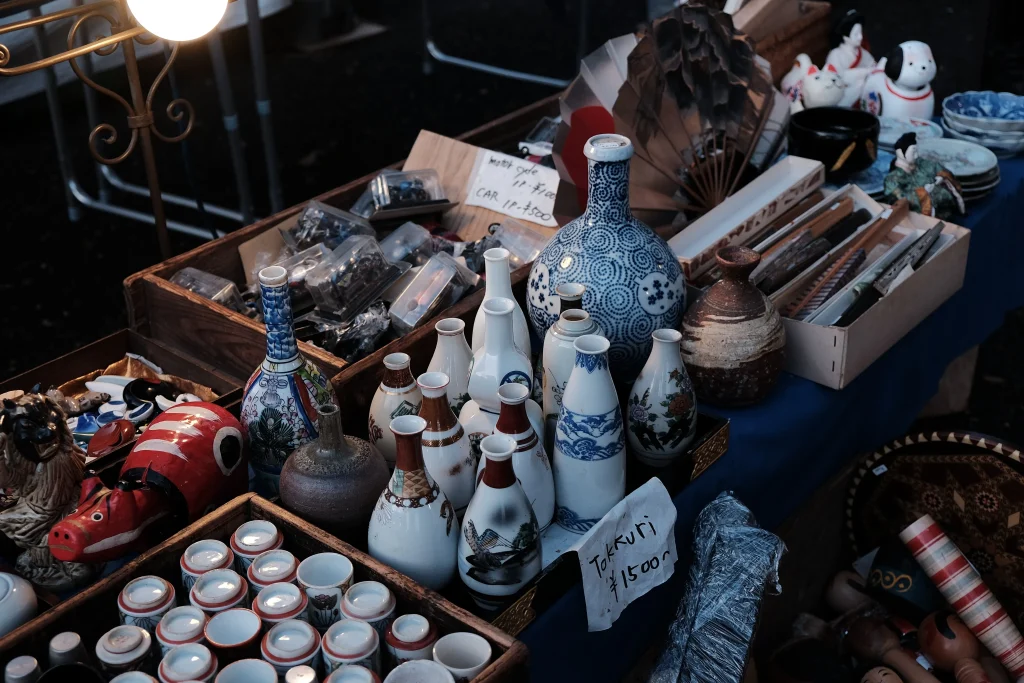 Vintage ceramics, sake bottles, and Japanese antiques displayed at a traditional flea market in Japan