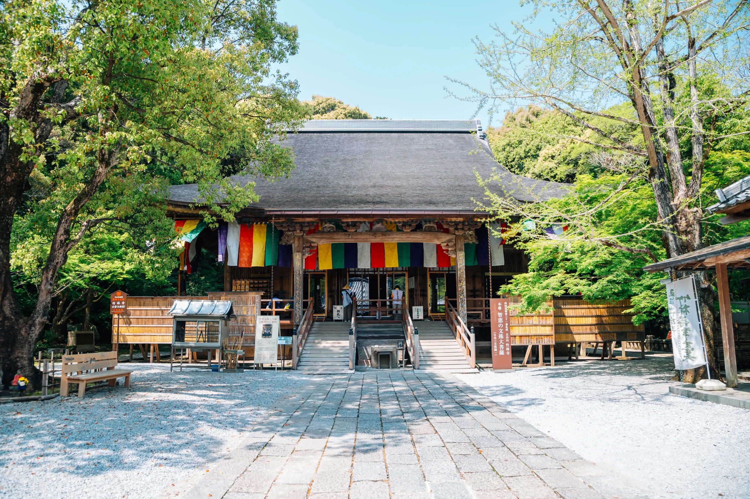 Main hall of Chikurin-ji Temple with colorful banners among green trees, Kochi
