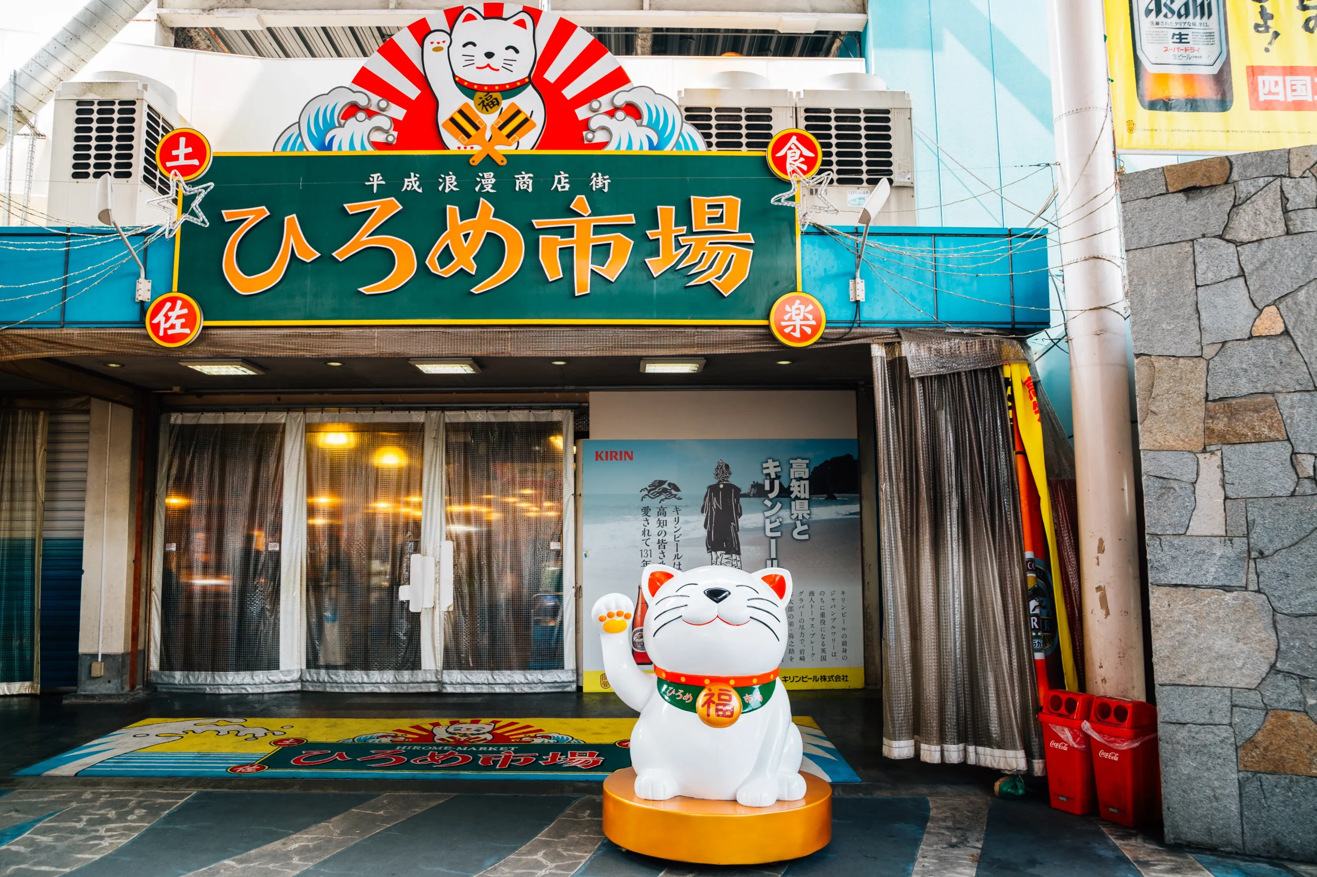 Entrance of Hirome Market with a lucky cat statue and sign in Kochi