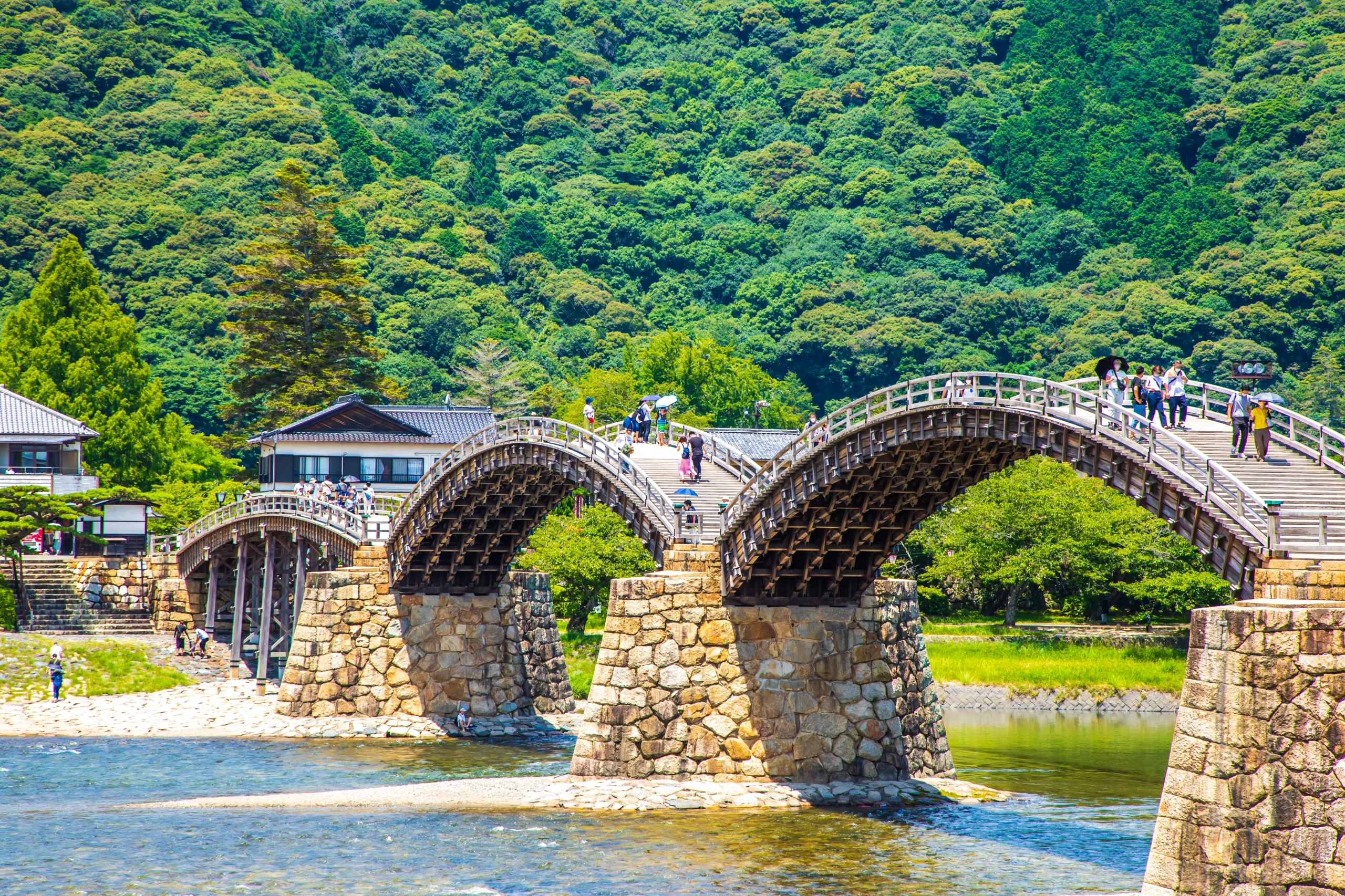 Wooden arched Kintaikyo Bridge over the river with green mountains in Iwakuni