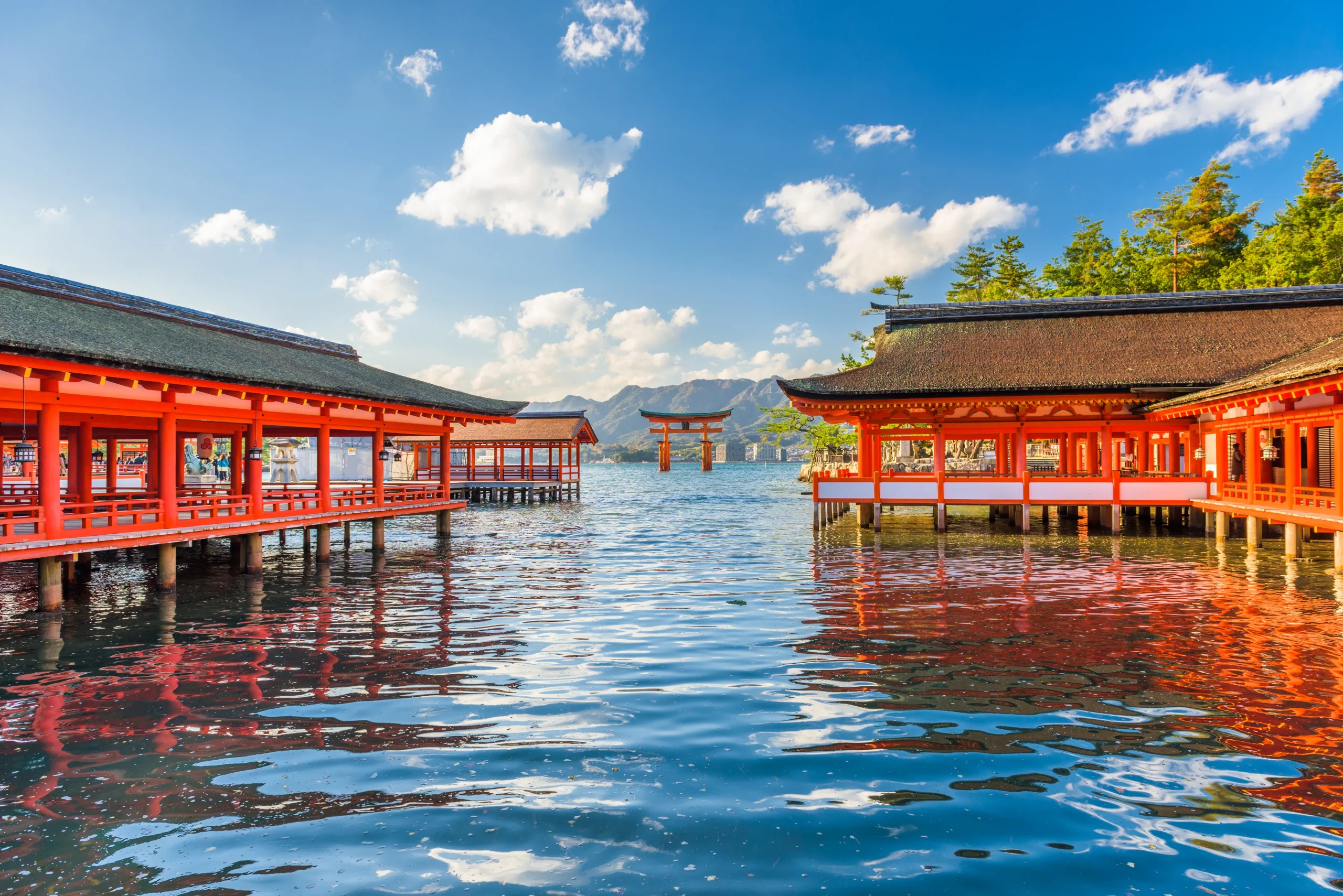 Vermilion halls of Itsukushima Shrine over the water with the floating torii on Miyajima