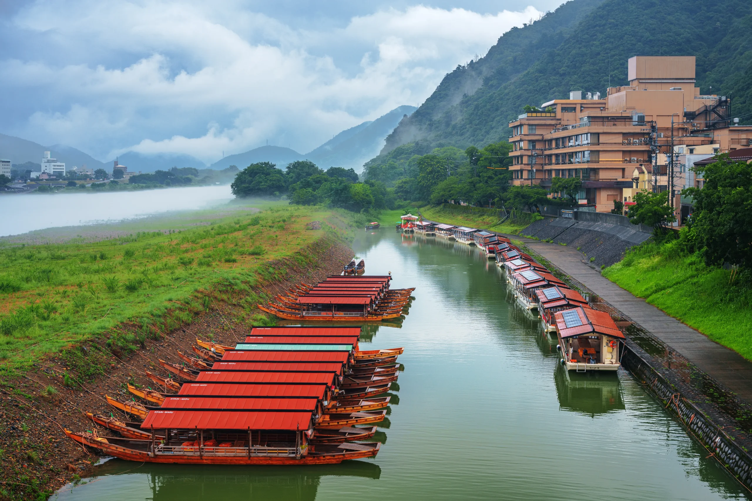 Row of red-roofed cormorant fishing boats moored on the misty Nagara River, Gifu