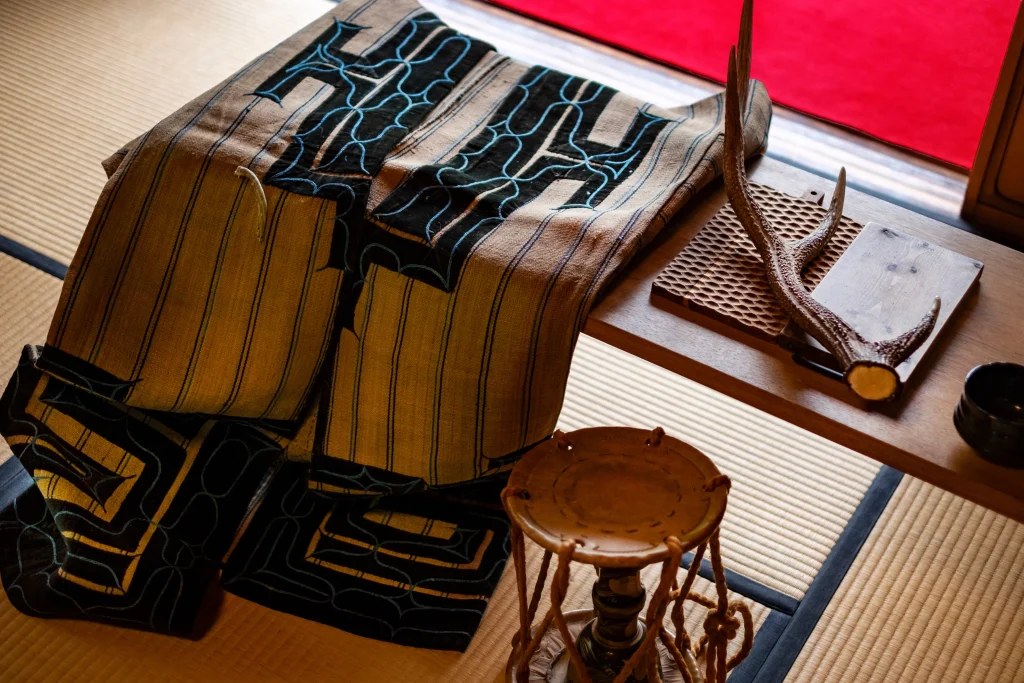 Ainu traditional embroidered robe on display in a tatami room in Hokkaido, Japan, with deer antler craft.