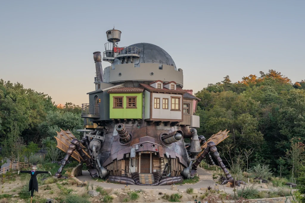 Life-sized Howl's Moving Castle with mechanical legs at dusk in the Valley of Witches at Ghibli Park