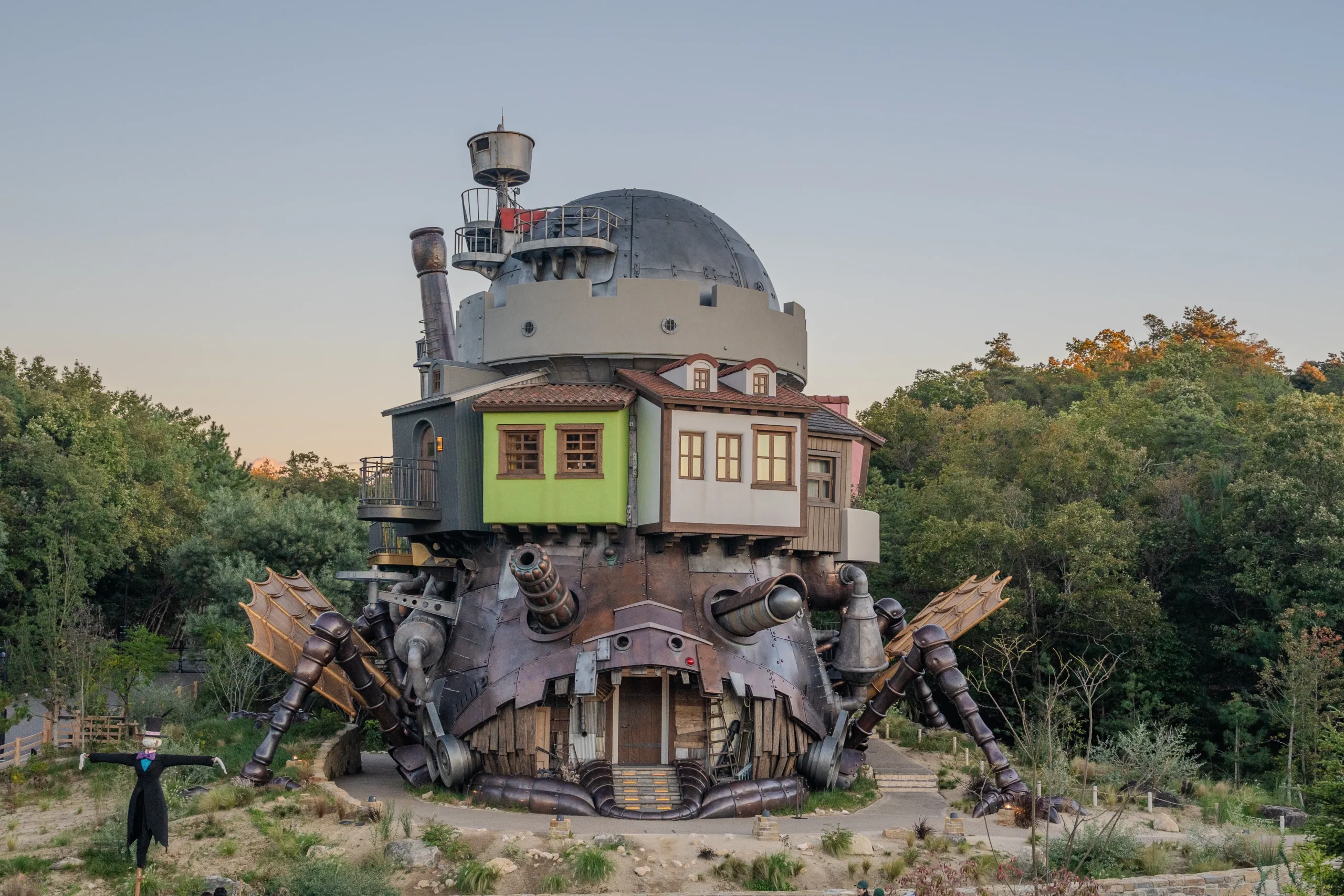 Life-sized Howl's Moving Castle with mechanical legs at dusk in the Valley of Witches at Ghibli Park