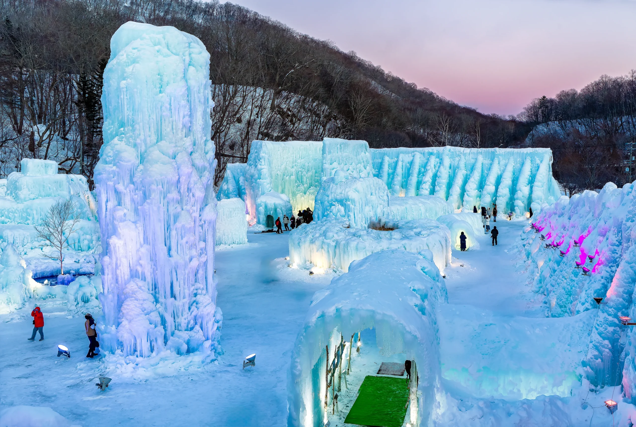 Illuminated blue ice towers at a Hokkaido winter ice festival at dusk
