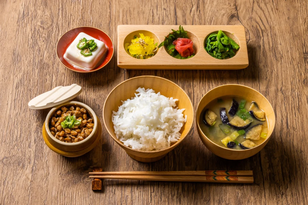 Traditional Japanese breakfast set with rice, miso soup, natto, tofu, and pickles