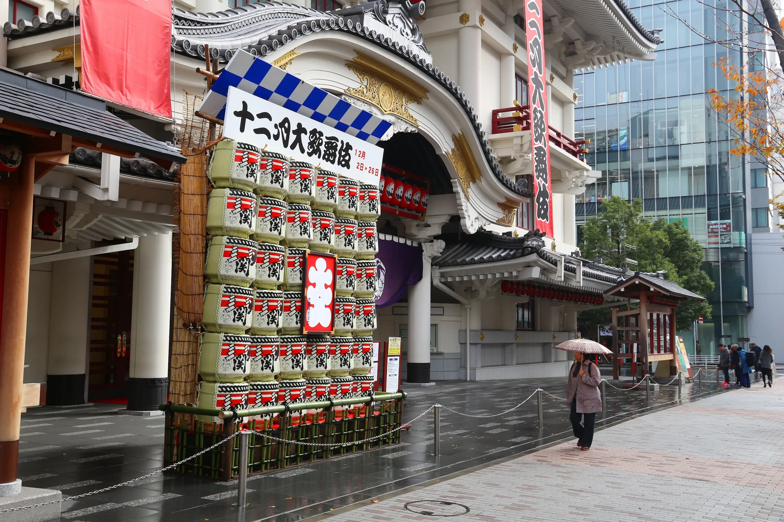 Facade of Kabukiza Theatre in Ginza, Tokyo, with stacked sake barrels and banners on a rainy day.