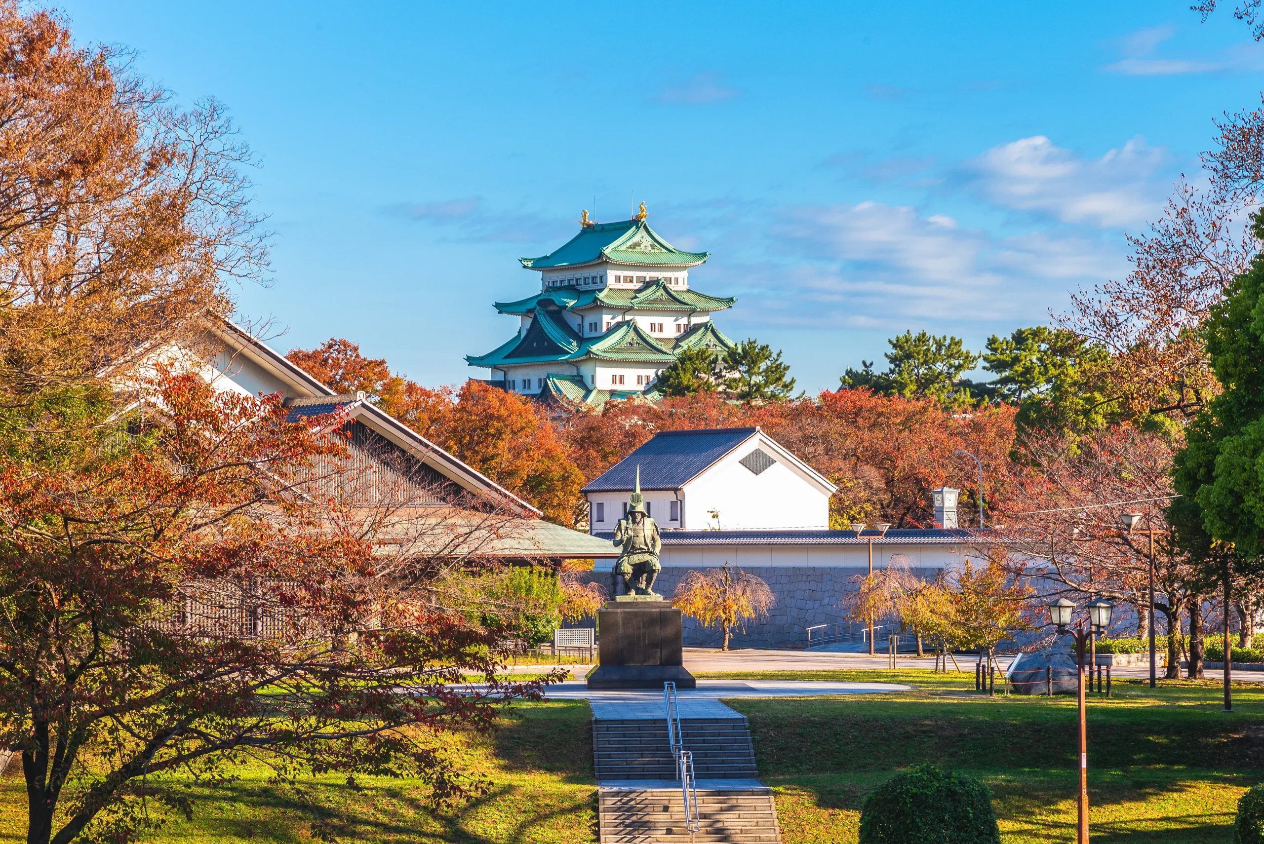 Nagoya Castle with green roofs and golden shachi behind autumn foliage