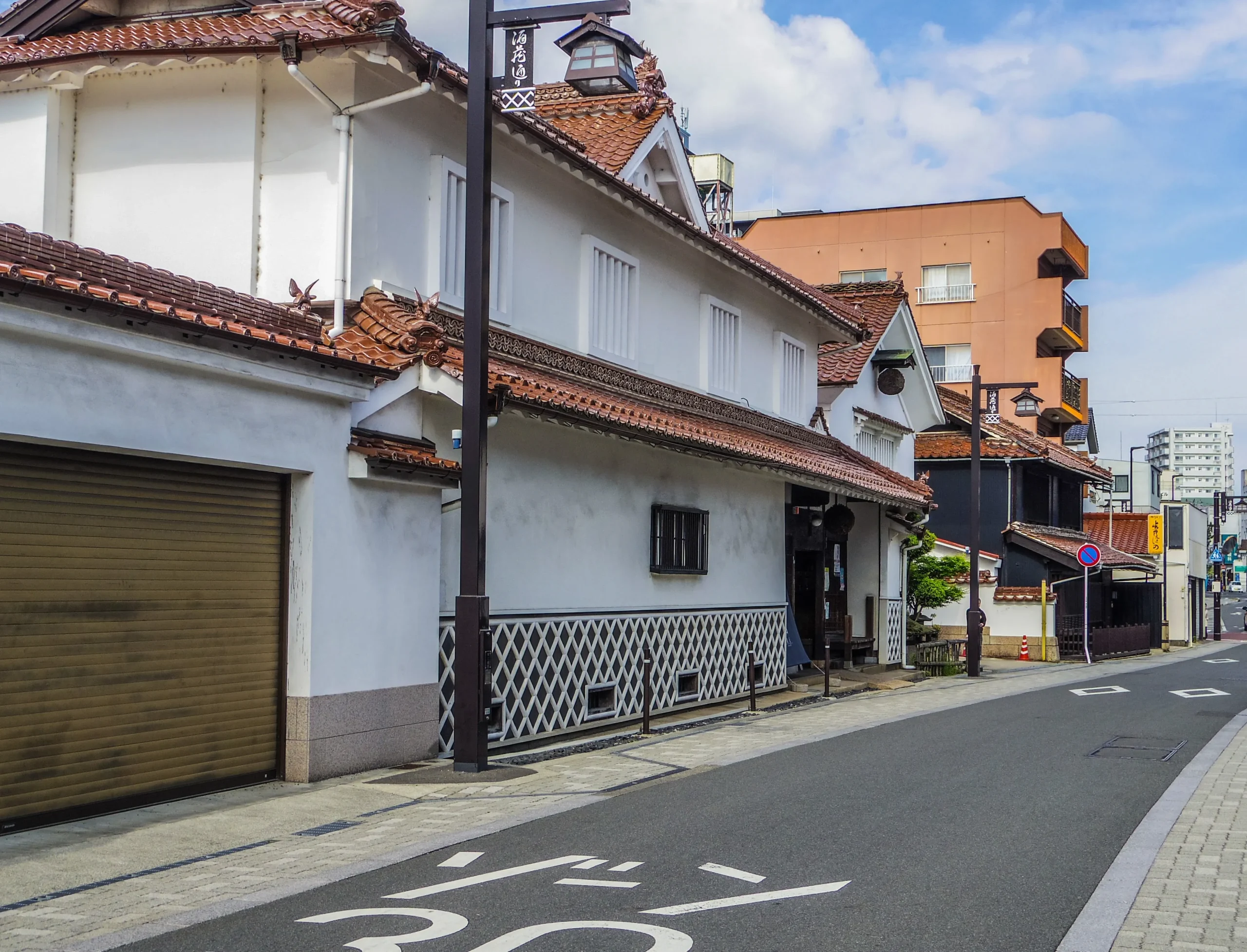 White-walled sake breweries with red-tiled roofs along a street in the Saijo sake district