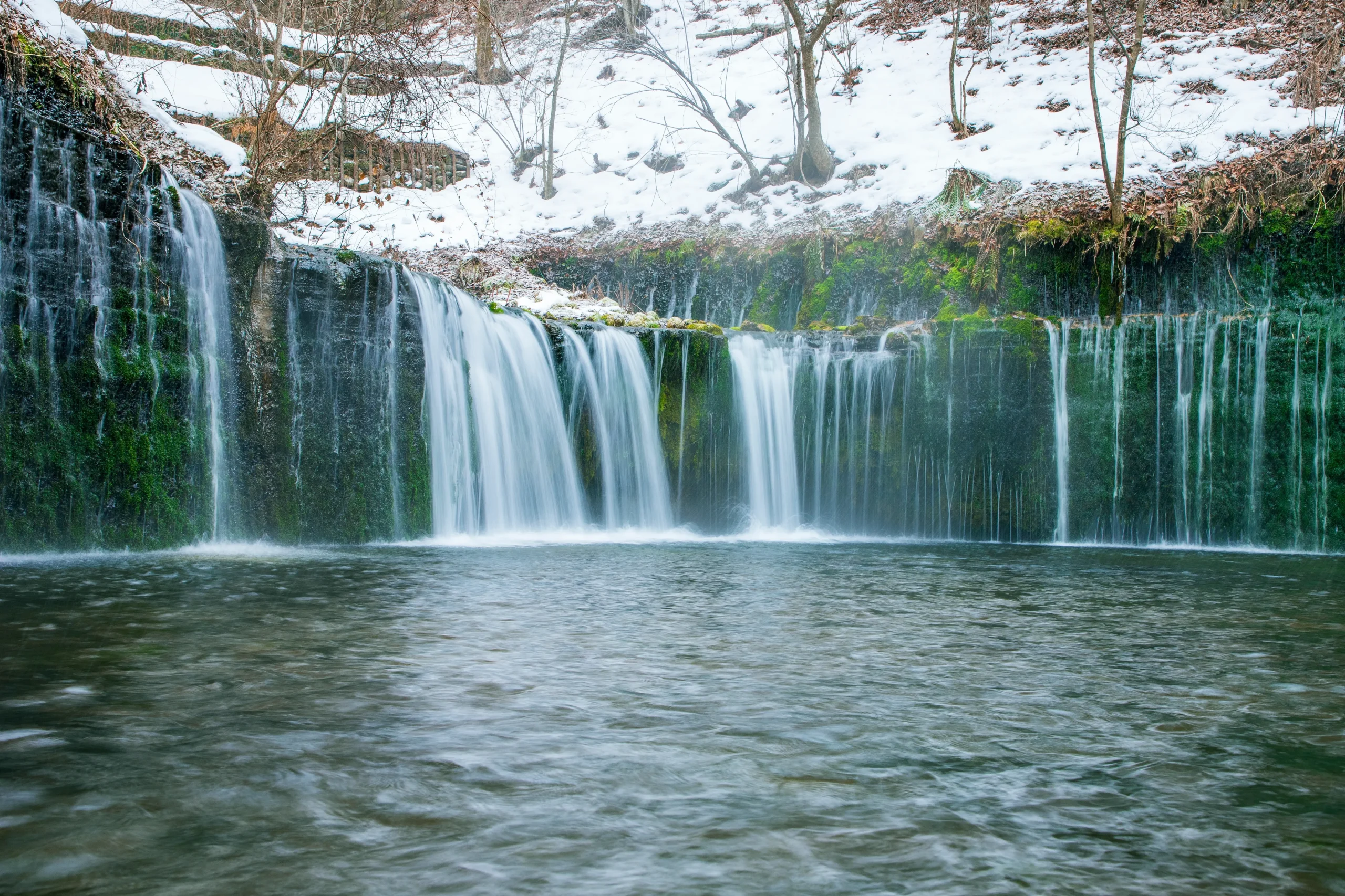 Shiraito Falls with silky cascading water over mossy rocks in winter, Karuizawa