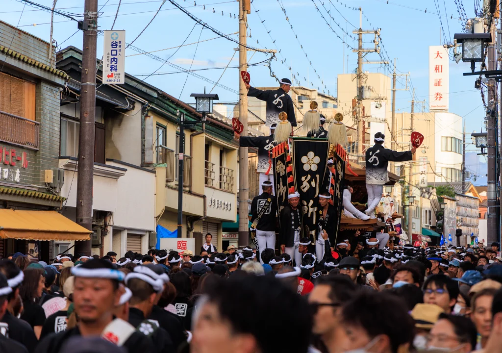 Festival participants riding and pulling a traditional danjiri float through the streets of Kishiwada, Osaka