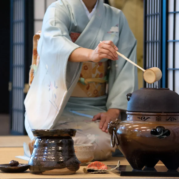 Japanese tea ceremony with woman in kimono preparing matcha using traditional tool
