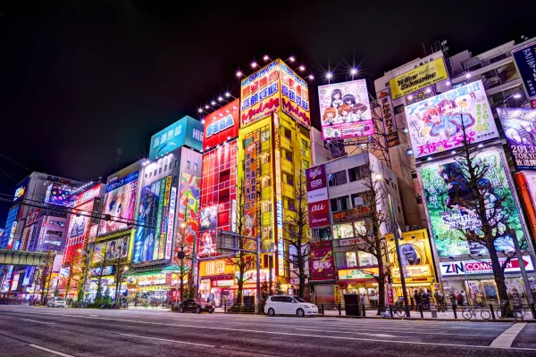 Neon-lit night view of Akihabara filled with anime advertisements, gaming shops, and vibrant city energy