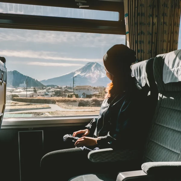 Woman enjoying Mt. Fuji view from train window during scenic ride in Japan